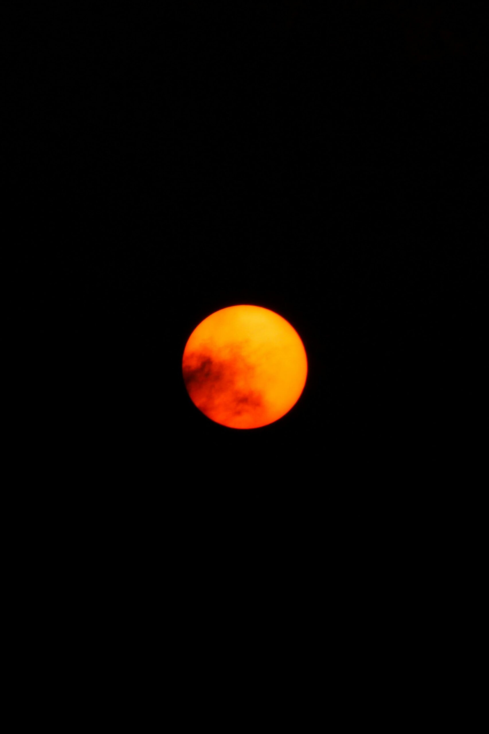 Vivid orange moon illuminating the dark night sky, capturing celestial beauty.
